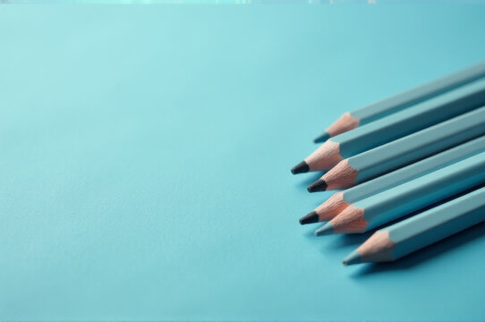 A collection of colorful pencils arranged on a bright blue background