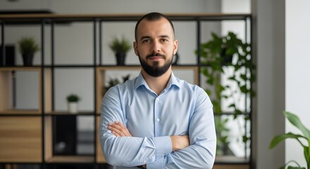 A confident businessman stands in his stylish office space, arms crossed with a composed and professional demeanor. Captured with a candid, authentic approach.