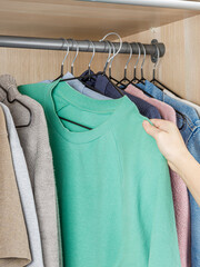 Obraz premium A person is in the process of taking a green sweater out of a closet