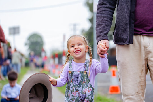 Little aussie girl holding parents hand waiting for ANZAC day parade march