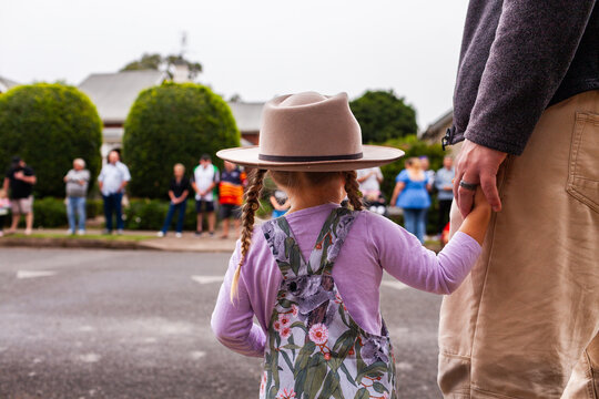 Little aussie girl holding parents hand waiting for ANZAC day parade march