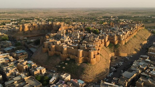 Aerial drone shot highlighting the intricate architecture of Jaisalmer Fort during a vibrant desert sunset.