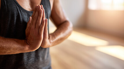 Man practicing yoga with hands pressed together in a namaste pose, representing mindfulness, gratitude, and physical discipline in a peaceful indoor environment