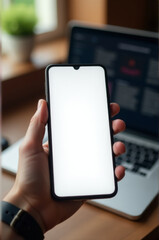 A person holds their phone in front of a laptop, showing how technology is used to multitask