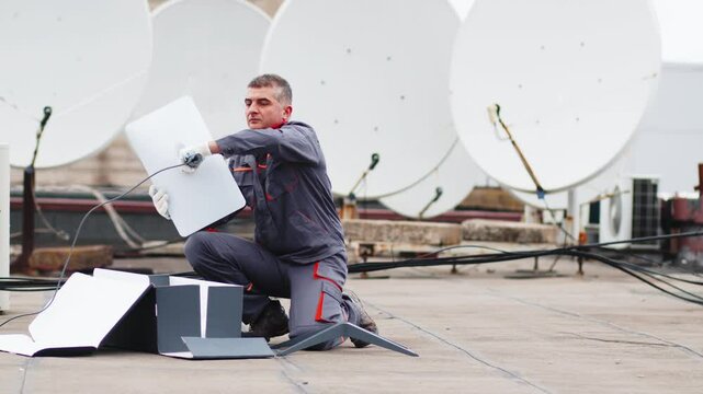 Telecommunication internet connection concept, industrial production station concept. Television worker, engineer, technician sets up an innovative satellite dish for the Internet.