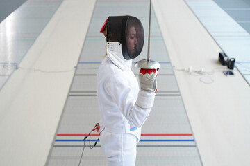 A fencer in full gear holding a sword on a fencing piste.