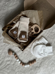 Beige socks with a brown bear and a wooden elephant teether in a box, scratches and beads next to the bed. The neutral pastel beige color of the accessories. Flatley