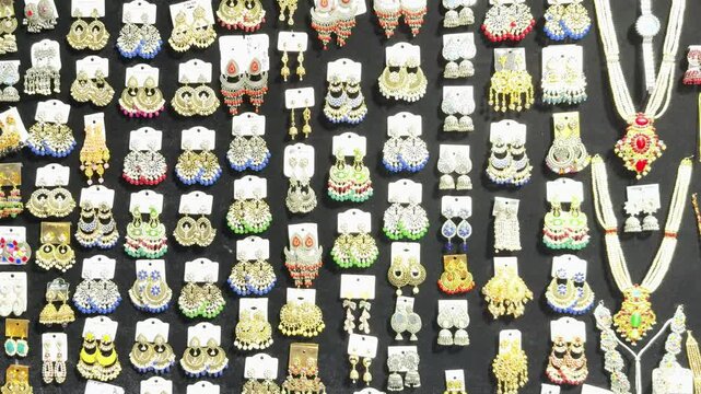Various colorful Indian earrings dangle on cards against a dark background at a jewelry shop