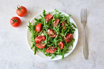 Arugula Salad with Tomatoes and seeds with a fork top view