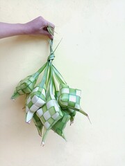 Ketupat is traditional food from Indonesia made from young coconut leaves for cooking rice during Eid Mubarak, Eid al Fitr. Isolated on light background.