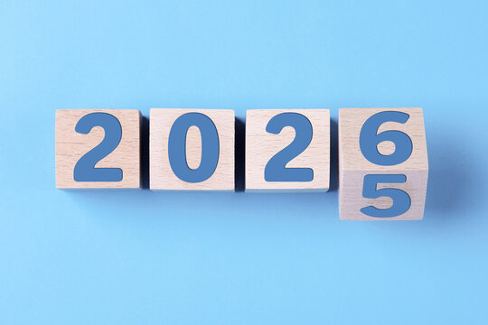 2026 Happy New Year. Wooden cube block change from 2025 to 2026 on blue. Concept 2026 New Year background. Business, resolutions, goals, inspiration, success, ideas