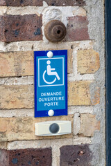 panneau de demande d'ouverture de porte pour accès handicapé sur un mur