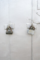 Locks secured on a weathered white door in an urban setting during daylight