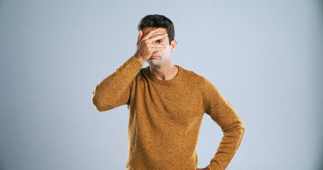 Hiding, face and man in studio, disappointed or sports fan with shame for loss and white...