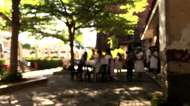Defocused video footage of devoted Catholics lining up to register for the sacrament of confirmation in the churchyard.