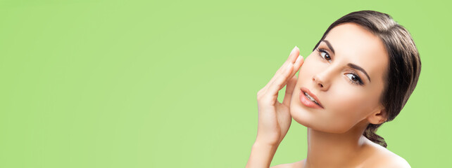 Portrait - beautiful woman touches her face, isolated green background with free text space. Brunette hair cute girl - beauty, glamour, fashion, makeup, skin care scincare spa concept. Banner image