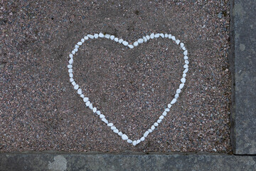 A heart shape formed from smooth stones is placed gently on a grave, symbolizing love and remembrance