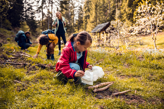 Young girl and family picking up litter in a forest during a hike