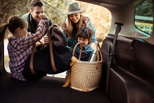 Family packing car trunk together for weekend road trip adventure