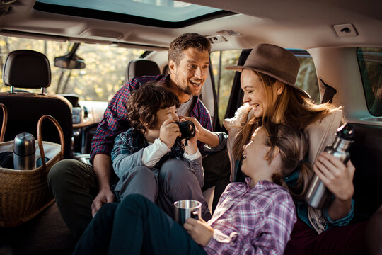 Happy family sitting in car taking pictures during road trip