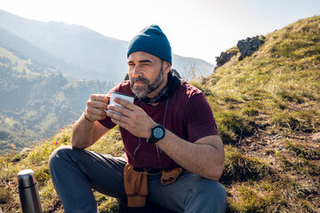 Man enjoying coffee while hiking in the mountains