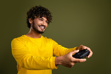 Portrait of a Stylish Young Man Holding a Game Controller and Smiling Against a Khaki Green...