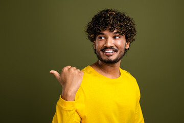 Portrait of a cheerful young man in stylish yellow shirt with curly hair, gesturing thumb up,...