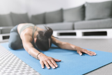 Practicing yoga with a child pose on a blue mat in a cozy indoor space with comfortable seating
