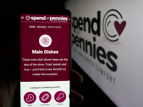 Stuttgart, Germany - 05-26-2025: Person holding cellphone with webpage of company Spend With Pennies (SWP Media Ltd.) on screen in front of logo. Focus on center of phone display.