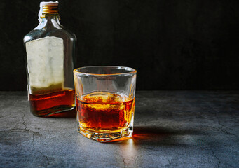 Strong alcohol drink and whiskey bottle Whisky in glass with ice, Whisky, bourbon or cognac. Hard strong alcoholic drink