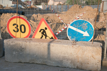 Traffic signs indicating construction zone with speed limit and directions near a road work site