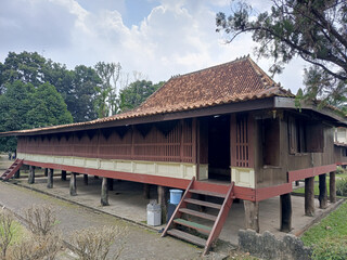 Elevated Wooden House with Brown Tiled Roof and Lush Green Trees