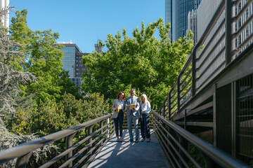 Business people walking and talking on bridge in urban park