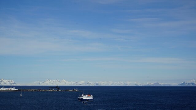 Blick auf das Meer in Longyearyen, Spitzbergen mit einem Boot und schneebedeckten Bergen am Polarkries