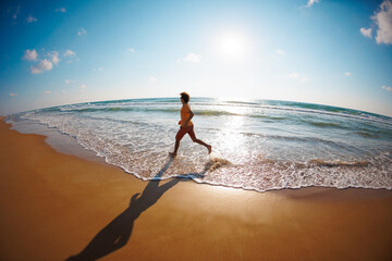 man runs barefoot along the beach by the sea. Powerful runner, sprint and summer training. A young...