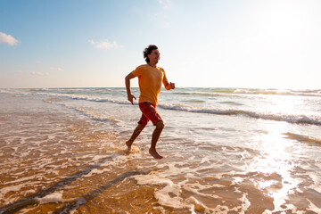 athletic man runs along the beach. fitness training on a sunny summer day. running on the sand.