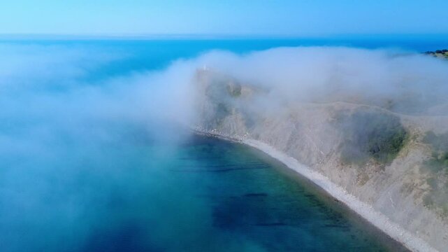 Aerial panoramic view of Cape Emine on the Bulgarian Black Sea coast. Dramatic cliffs, a historic lighthouse, and turquoise waters shrouded in mysterious sea mist, captured by drone.