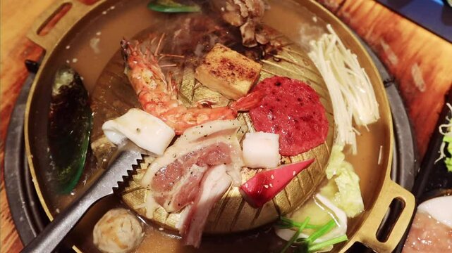 Top view of the traditional asian grill or hot pot in Thail restaurant cooking seafood and meat