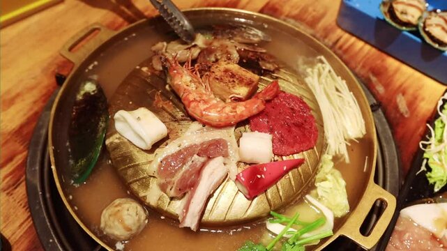 Top view of the traditional asian grill or hot pot in Thail restaurant cooking seafood and meat