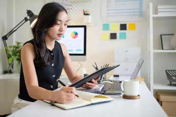 Young businesswoman in a jotting down important tasks while working in a bright office space.