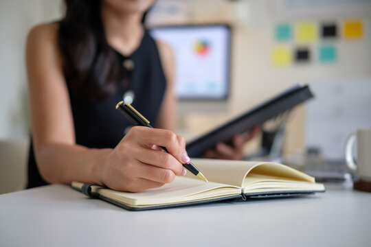 Young businesswoman in a jotting down important tasks while working in a bright office space.