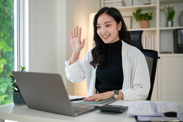 Friendly businesswoman ttending a virtual meeting, greeting colleagues with a cheerful expression.