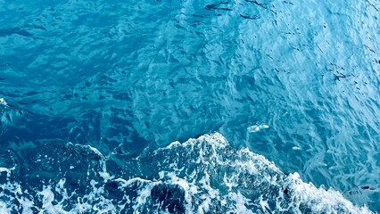 Top view of azure waves in the Mediterranean Sea. Sea background, summer vacation, travel, coastal scenery, turquoise water, Mediterranean nature, relaxing seascape. 