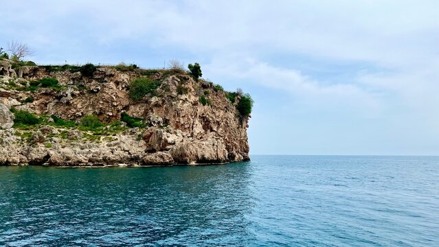 Turquoise sea with rocky cliff view. Summer vacation, Mediterranean Sea, travel, coastal landscape, nature, Antalya province, Turkey, outdoor scenery, peaceful summer day.
