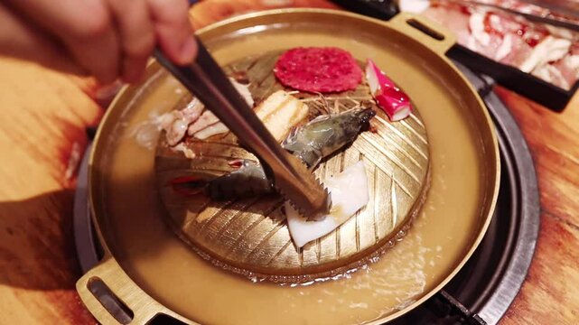 Top view of the traditional asian grill or hot pot in Thail restaurant cooking seafood and meat