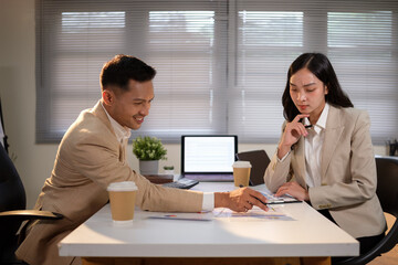 Two colleagues collaborating in a modern office, reviewing charts and discussing project data.