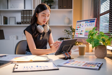Creative female graphic designer working with digital tablet at cozy home office deskCreative female graphic designer working with digital tablet at cozy home office desk