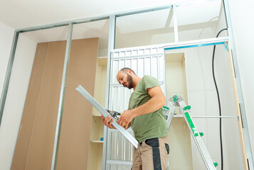 Construction worker building plasterboard wall for a sliding door wardrobe