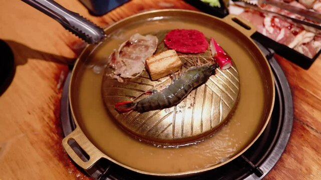 Top view of the traditional asian grill or hot pot in Thail restaurant cooking seafood and meat