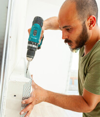 Construction worker installing drywall corner bead using cordless screwdriver